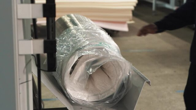 Close-up of compressed mattress wrapped in stretch film on a factory automated packaging line for compressed mattresses