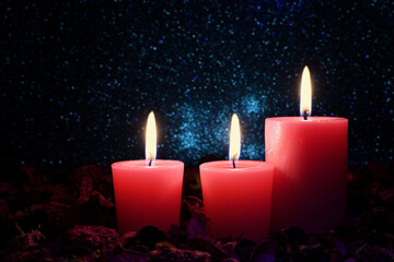 Three aromatic lit pink candles surrounded by potpourri blue sparkly star-like background dark mood lighting