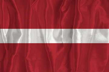 The flag of Latvia on a silk background is a great national symbol. Texture of fabrics The official state symbol of the country