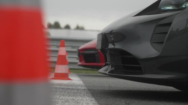 red and black car ready to start drag race waiting behind start line with cones in foreground in 4k