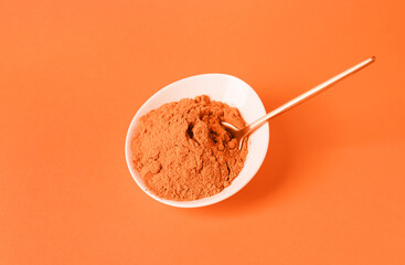 Bowl of powdered spice on orange background