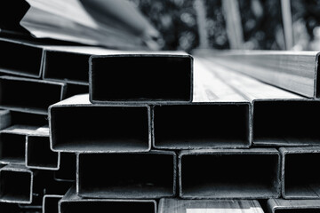 Group of square steel rectangle tubes metal iron production profiles pipe on the ground. Square metal pipes for background using metal pipes and rods, steel materials, building materials.