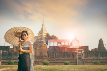 asian woman wearing thai traditional suit stand with umbrella against old temple in ayutthaya world heritage of unesco thailand
