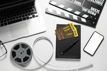 Movie clapper with reel, laptop, notebook, tickets and mobile phone on white background