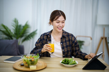Happy beautiful Asian woman eating healthy food with vegan.salad in the kitchen at home.