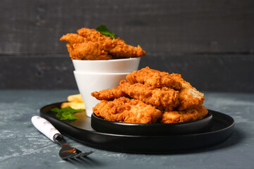 Plate with tasty nuggets on dark table