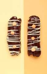 Tasty chocolate eclairs on yellow and orange background