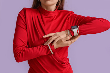 Woman with smartwatch and bracelets on lilac background, closeup