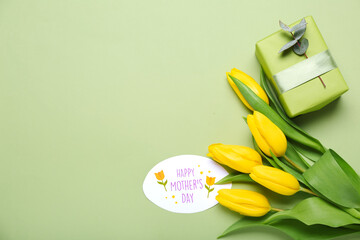 Greeting card with text HAPPY MOTHER'S DAY, gift box and beautiful tulip flowers on green background