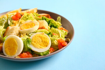 Plate of delicious salad with boiled eggs and salmon on blue background
