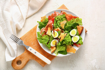 Plate of delicious salad with boiled eggs and jamon on white grunge background