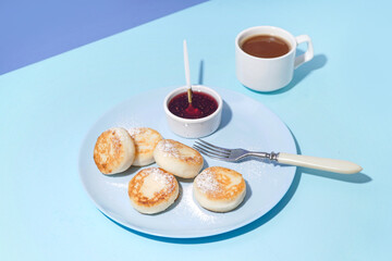 Plate with tasty cottage cheese pancakes, strawberry jam and cup of coffee on color background