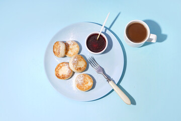Plate with tasty cottage cheese pancakes, strawberry jam and cup of coffee on color background