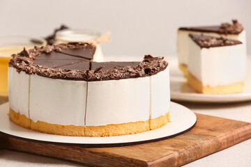 Wooden board with tasty birds milk cake on light table, closeup