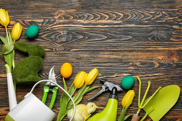 Gardener's tools with Easter eggs, rabbit, chicken and tulips on dark wooden background