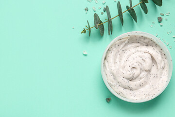 Jar of body scrub and eucalyptus branch on color background