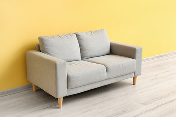 Stylish grey sofa near yellow wall