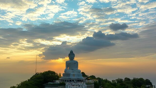 aerial hyper lapse view Phuket big Buddha in beautiful sunset..the sun shines through the clouds impact on ocean surface.The beauty of the statue fits perfectly with the charming nature..cloud scape 
