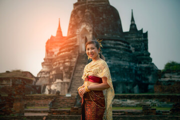 beautiful asian woman wearing thai tradition dress smiling with happiness  standing against old stupa in ayutthaya world heritage site of unesco near bangkok thailand - obrazy, fototapety, plakaty