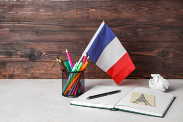 Flag of France with stationery on table near dark wooden wall
