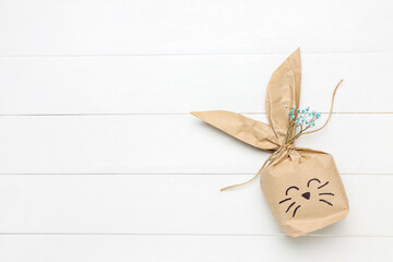 Easter bunny gift bag with gypsophila flowers on white wooden background