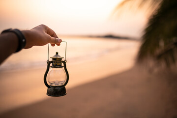 A Beautiful Sea side background at sunset, a Vintage lamp held in a hand Ramadan and Eid concept...