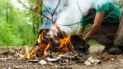 Man preparing barbecue fire for cooking meats at mountain forest camp. Fire flames and smokes of a...