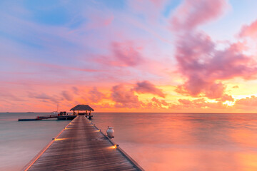 Amazing sunset landscape. Picturesque summer sunset in Maldives. Luxury resort villas seascape with soft led lights under colorful sky. Dream sunset over tropical sea, fantastic nature scenery
