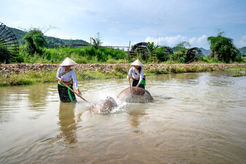 Ethnic minority women catch fish in streams