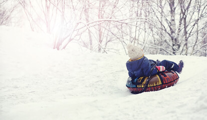 Children in the park in winter. Kids play with snow on the playground. They sculpt snowmen and slide down the hills.