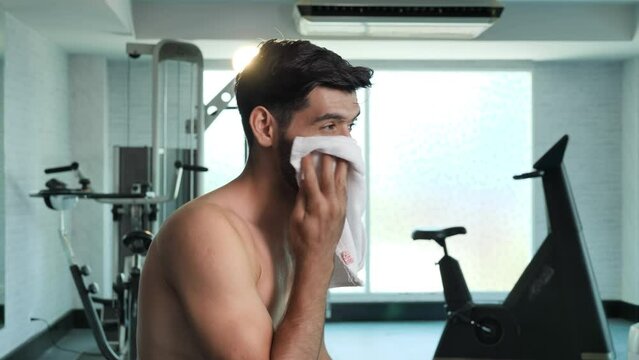 Slow motion shot, Middle eastern male use a towel to wipe sweat after gym training. Fitness gym, Healthy lifestyle, a 25-year-old man