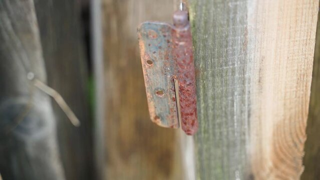 Old rusty door hinge on a wooden beam close-up, smooth camera movement