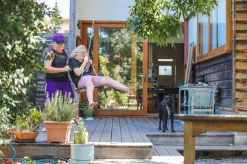 Two brothers playing together on backyard swing on bright spring day