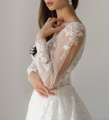 Bride dressed in a white wedding dress with a deep neckline, laced corset and fancy long sleeves....