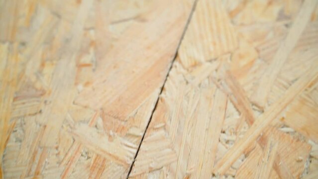 Oriented Strand Board screwed with black self-tapping screws close-up. Connection of two osb plates. Smooth camera movement along the seam in the subfloor