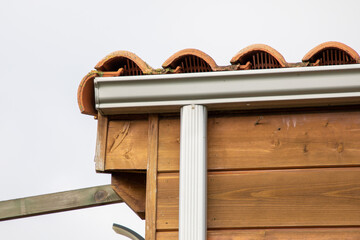 white rain gutters wooden facade roof tiles on new modern home