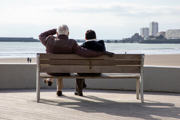 senior man woman couple retired in love on beautiful water sea coast beach back view behind