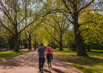 Woman with preteen daughter and teenage son walking in city park in spring