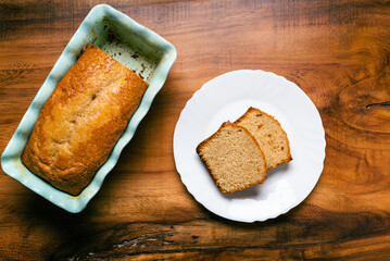 Homemade sponge cake in blue ceramic mold on wooden table. Sliced Pound cake.