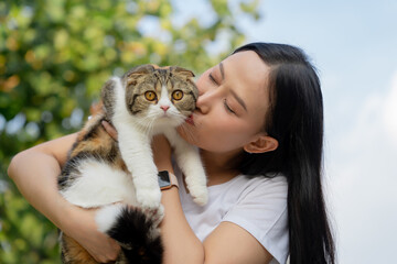 Obraz premium Beautiful young girl holds a Scottish cat with orange eyes, outdoor, close-up