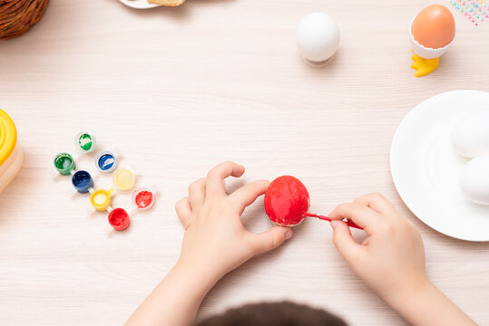 Child hands painting easter eggs, selective focus. Happy Easter concept. Process of crafting at home. Greeting card with copy space
