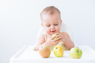 cute baby girl in baby chair eating apples. Baby first solid food