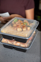 A view of several plastic to-go containers ready for pick up on a restaurant counter.