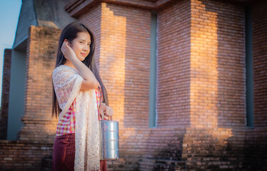 In the evening light a beautiful thai woman is standing and looking to the copy space in a close-up shot with smile on her face.