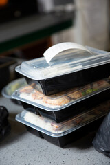 A view of several plastic to-go containers ready for pick up on a restaurant counter.