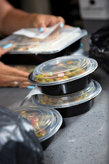 A view of several plastic to-go containers ready for pick up on a restaurant counter.
