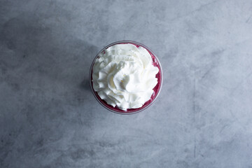 A top down view of a blueberry smoothie with whipped cream.