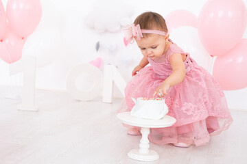cute little child girl eating birthday cake and celebrating her first birthday