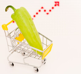Green pepper in a toy consumer basket against the background of an inflation growth arrow. Rising...