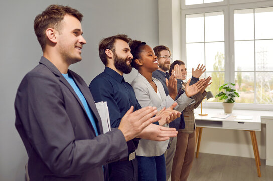 Multinational people working in same company applaud after performance or refresher training and participate in team building activities stand in office along wall. Corporate culture concept